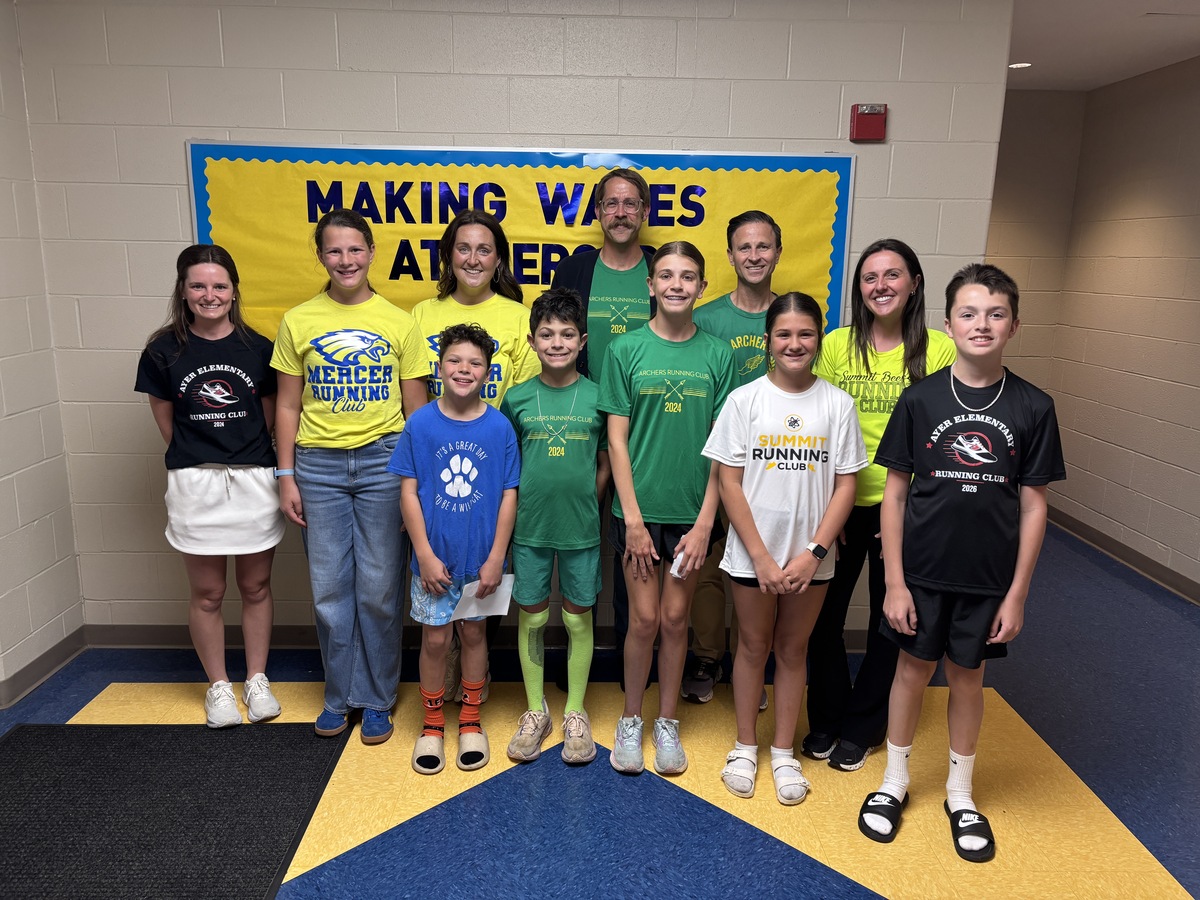 Elementary run club participants and coaches pose for a photo inside the school